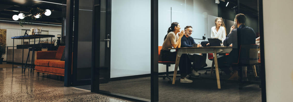 Business colleagues having a meeting in a transparent boardroom discussing capital gains share sales