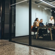 Business colleagues having a meeting in a transparent boardroom discussing capital gains share sales